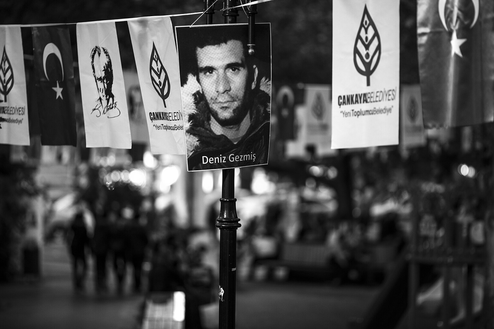 Foto von Deniz Gezmiş im Jahr 2014 in Ankara Fotografie eines jungen Mannes an einem Laternenpfahl, daneben andere politische Plakate