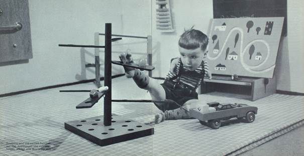 Schwarz-Weiß-Fotografie eines kleinen Kindes am Spielen. Die Spielsachen bewegt es mit den Füßen, da es keine Arme hat.