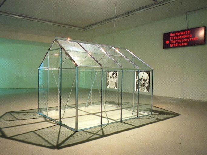 Beate Passow, Eichmann-Installation: „Ein Mann wohnt im Haus“ (aus dem Gedicht von Celan „Todesfuge“), Kunstforum der Städtischen Galerie im Lenbachhaus, München - 26. Januar bis 23. Februar 1990 (© mit freundlicher Genehmigung der Künstlerin [http://www.beate-passow.de Beate Passow]). 
Das fotografische Porträt Adolf Eichmanns nach seiner Entführung 1960 aus Argentinien nach Israel zählt zu den Medienikonen des 20. Jahrhunderts. Im Glaskasten des Jerusalemer Gerichts musste sich der ehemalige Leiter des Judenreferats im Reichssicherheitshauptamt wegen Massenmordes an den Juden Europas verantworten. Geschickt verstand es Eichmann, sich auf der Bühne seines Glaskastens als serviler Befehlsempfänger zu inszenieren. Zu Medienikonen gehört es, dass sie auch in künstlerischen Zusammenhängen zitiert und kommentiert werden. In dem Glashaus der Münchner Künstlerin konnte das Urteil im Eichmann-Prozess über Kopfhörer angehört werden, außerhalb des Glashauses die Anklage, beides gesprochen von Harry Mulisch. Die beiden Fotos zeigen Eichmann: einmal die rechte Seite verdoppelt und einmal die linke – eine Praxis, die in der Psychiatrie angewandt wurde, um die beiden Seiten eines Menschen zu zeigen.
<br />
Ausführlich zur „Karriere“ der Eichmann-Fotografien siehe Gerhard Paul, „The Man in the Glass Box“. Die mediale (Selbst-)Inszenierung Eichmanns und der Täter-Diskurs, in: ders., BilderMACHT. Studien zur Visual History des 20. und 21. Jahrhunderts, Göttingen 2013, S. 397-434.