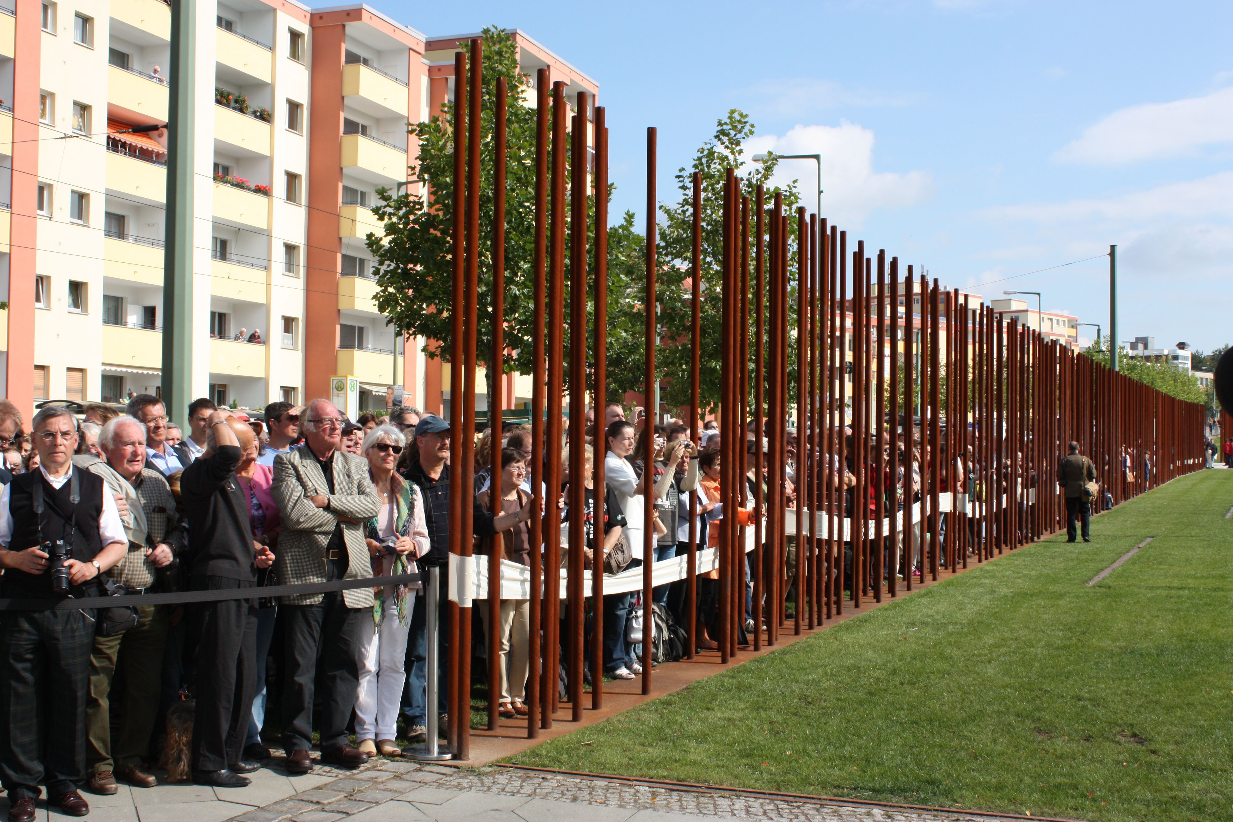 „Mauer“ Bernauer Straße, Foto: Hans-Hermann Hertle ©, Berlin, 30.6.2012<br /> 
Einweihung des zweiten Teils der Außenausstellung an der Gedenkstätte Bernauer Straße am [http://www.berliner-mauer-gedenkstaette.de/de/50-jahre-mauerbau-892.html 50. Jahrestag des Mauerbaus]. Während der Mauerverlauf teils durch Metallstäbe nachzuvollziehen bleibt, stehen an anderen Stellen der 2014 fertiggestellten [http://www.berliner-mauer-gedenkstaette.de/de/entstehungsgeschichte-211.html „neuartigen Erinnerungslandschaft“] Mauerreste unter Denkmalschutz: „Die bestehenden Reste und Spuren der Berliner Mauer wurden dabei erhalten, die dramatische Ereignisgeschichte der Bernauer Straße wird erlebbar.“