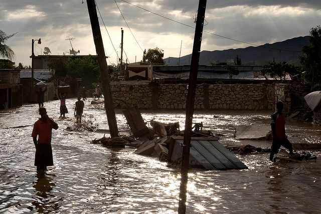 Naturkatastrophen: Tropische Stürme und Überschwemmungen. Haiti, 9. September 2008. „Tropical Storm Hanna Floods Gonaives. People walk through the flooded streets of Gonaives, Haiti. 8 days after tropical storm Hanna swept through the area.” Photo ID 192484. 09/09/2008. Gonaives, Haiti. Quelle: [https://www.unmultimedia.org/photo/ UN Photo Logan Abassi] / [https://www.flickr.com/photos/un_photo/5479976200/ Flickr] ([https://creativecommons.org/licenses/by-nc-nd/2.0/ CC BY-NC-ND 2.0]).