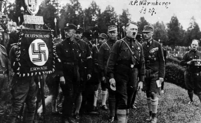 Nürnberg Reichsparteitag 1927, Gruppenaufnahme, von rechts: Franz Pfeffer von Salomon [Franz von Pfeffer], Adolf Hitler, Gregor Strasser, Rudolf Hess, Heinrich Himmler, rechts SA-Standarte. Fotograf unbekannt, Quelle: [https://commons.wikimedia.org/wiki/Category:Sturmabteilung?uselang=de#/media/File:Bundesarchiv_Bild_146-1969-054-53A,_N%C3%BCrnberg,_Reichsparteitag.jpg Wikimedia Commons] / Bundesarchiv Bild 146-1969-054-53A ([https://creativecommons.org/licenses/by-sa/3.0/de/deed.de CC-BY-SA 3.0]).