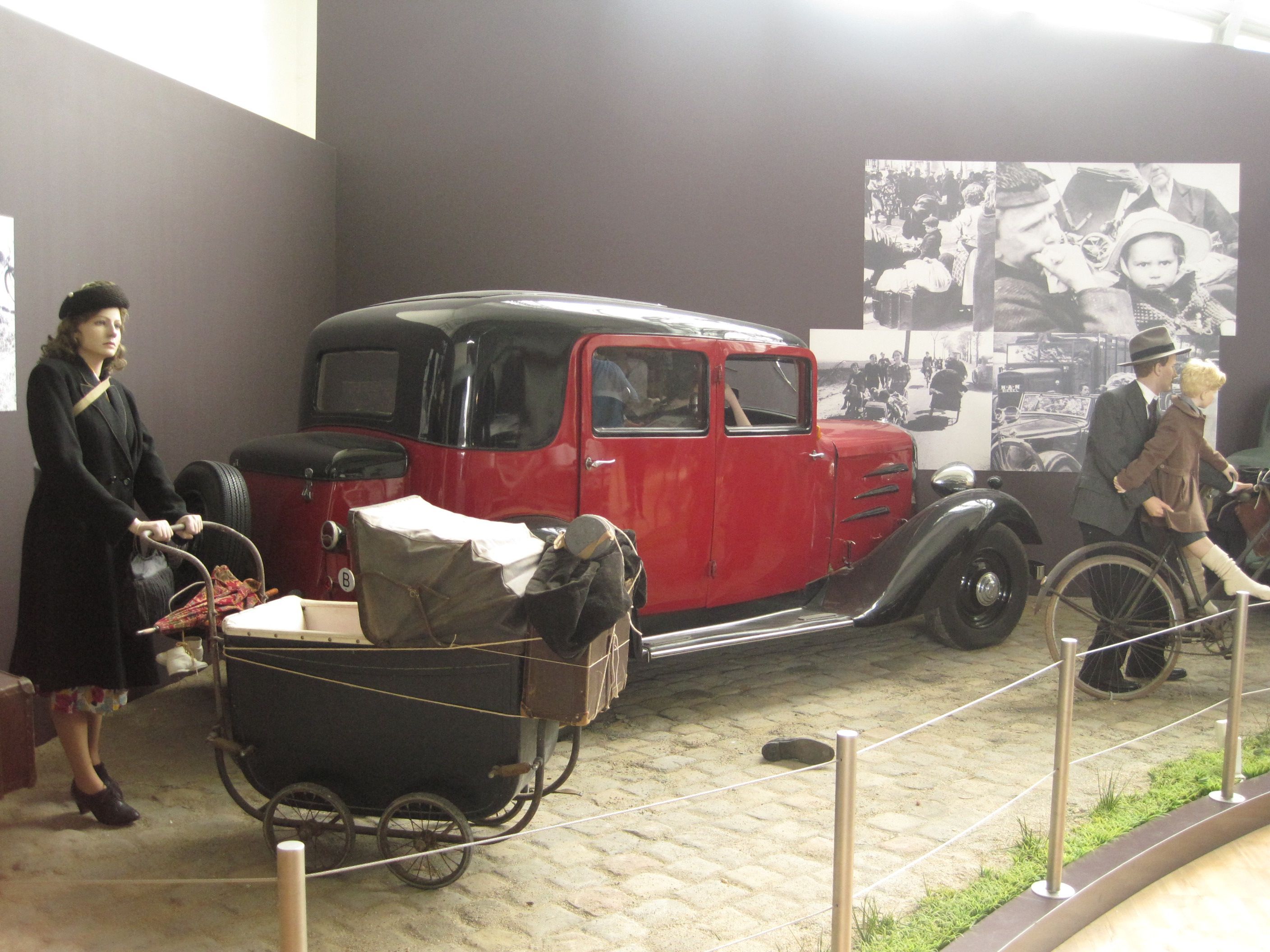 History is enacted here with the help of historical objects and mannequins. These are presented opposite historical photos, some of which show images similar to the street scenes enacted here, thereby authenticating them. Photo: Irmgard Zündorf, Military Historical Museum, Brussels 2015, License: [https://creativecommons.org/licenses/by-nc/3.0/de/ CC BY-NC 3.0 DE]