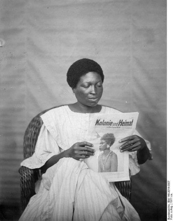 The illustrated magazine Kolonie und Heimat (Colony and Homeland) was the official publication of the Women’s League of the German Colonial Society. Its aim was to popularize the colonies in Germany and make them attractive as settlement areas. The African woman in a wicker chair and European reform clothing stands in contrast to the image on the magazine she’s holding in her hands, but suggests the possibility of Heimat in the colonies. The picture must have been disconcerting at the time, since Heimat was hardly associated with people living in the colonies, much less with African women displaying a dignified and sophisticated middle-class domesticity.
<br />
Kolonie und Heimat ca. 1911, b/w photograph 18 x 18 cm. The woman’s identity and the photographer are unknown. Source: Bundesarchiv Bild 146-2014-0007 courtesy of the German Federal Archives