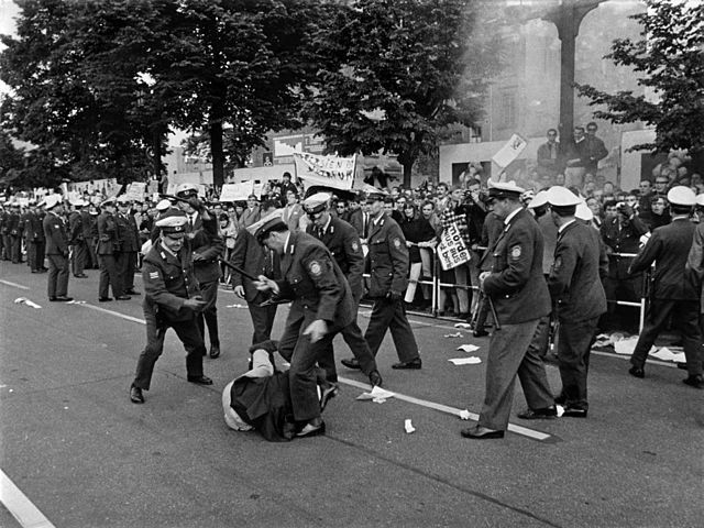 Der „kritische Moment“ eines Ereignisses: Schlagende Polizisten, bevor das berühmte Foto des erschossenen Demonstranten Benno Ohnesorg eine Wende einleitete. Studentenrevolte 1967/68, West-Berlin, Fotograf: Ludwig Binder; veröffentlicht vom Haus der Geschichte der Bundesrepublik Deutschland. Quelle: [https://de.wikipedia.org/wiki/Demonstration_am_2._Juni_1967_in_West-Berlin#/media/Datei:Ludwig_Binder_Haus_der_Geschichte_Studentenrevolte_1968_2001_03_0275.0155_(16870592987).jpg Stiftung Haus der Geschichte - 2001_03_0275.0155d / Wikimedia Commons], Lizenz: [https://creativecommons.org/licenses/by-sa/2.0/deed.en CC BY-SA 2.0]