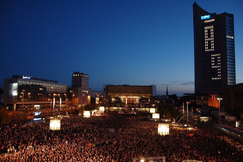 Der Festakt „Aufbruch Leipzig – 20 Jahre Friedliche Revolution und Einheit Europas“ am 9. Oktober 2009. Foto: Charlotte Noblet, Quelle: [https://www.flickr.com/photos/verni22im/3998887076/in/photolist-76nkNU-pGzsto-76nhmu-76niAw-76imYH-pEgo6d-pD2qPx-pBoR5X-pBF39c-digMsk-76xwVJ-pBUwLM-9ajt1E-pk1oh4-pFFsTz-7b2zfy-9ajrAj-pmi7vK-7aXHVe-pBWy49-9ajtLW-7binAr-9agiAH-8iZFuD-pE1Zdp-77KpMR-77KCNK-77PufL-7b2BEf-769Gww-79EYCN-79BaKp-765NfH-77KxT8-769Esf-77KApR-765MRx-77KwK2-77Kuya-765N6R-77Poqs-765MXn-765MDe-765Lrz-7uAhdc-765L6i-765Mpg-7uE9i9-769FQY-769ENA Flickr], Lizenz: [https://creativecommons.org/licenses/by-nc-sa/2.0/ CC BY-NC-SA 2.0]