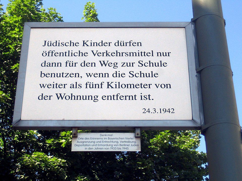 [https://www.berlin.de/ba-tempelhof-schoeneberg/ueber-den-bezirk/gedenken/artikel.358191.php Orte des Erinnerns im Bayerischen Viertel]: Denkmal zur Erinnerung an die Ausgrenzung und Entrechtung, Vertreibung, Deportation und Ermordung von Berliner Juden in den Jahren 1933 bis 1945. Tafel zum Verbot von öffentlichen Verkehrsmitteln für Schulkinder. Foto: Manfred Brueckels, Berlin 20008. Quelle: [https://commons.wikimedia.org/wiki/File:Bayerisches_Viertel_Erinnern_Schulweg.jpg Wikimedia Commons], Lizenz: [https://creativecommons.org/licenses/by-sa/3.0/deed.en CC BY-SA 3.0]