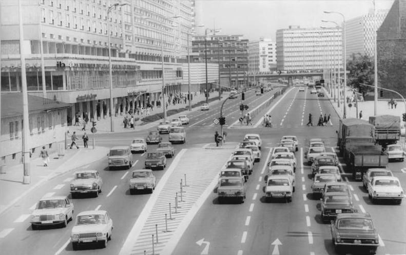 Die autogerechte Stadt: Karl-Liebknecht-Straße, Ost-Berlin 1974. ADN-Text: „Eine gelungene Verkehrslösung in der Hauptstadt findet man am S-Bahnhof Alexanderplatz: Seit zwei Jahren ist hier durch den Umbau des S-Bahnhofs und der breiter gestalteten S-Bahn-Überführung ein früheres Nadelöhr für den Verkehr beseitigt. Die Karl-Liebknecht-Straße gestattet mit ihren mehrspurigen Fahrbahnen jetzt auch bei starken Fahrzeugströmen ein zügiges Durchfahren.“ Fotograf: Horst Sturm, Ost-Berlin, 24. Juni 1974. Quelle: [https://www.bild.bundesarchiv.de/dba/de/search/?query=Bild+183-N0627-317 Allgemeiner Deutscher Nachrichtendienst, Bundesarchiv, Bild 183-N0627-317], Lizenz: [https://creativecommons.org/licenses/by-sa/3.0/ CC-BY-SA 3.0]