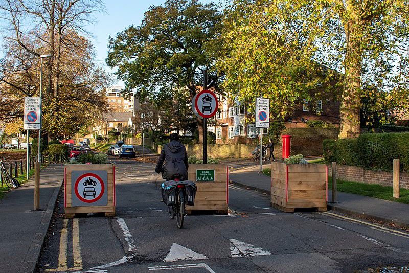 Verkehrsberuhigtes Stadtviertel:  Low Traffic Neighbourhood (LTN) trial, Lower Ham Road, Kingston upon Thames, 2020: „The modal filter allows cycles and pedestrians to pass – the circular signs indicate that no motor vehicles are allowed through.“ Fotograf: Jack Fifield, Kingston upon Thames, 2. November 2020, Quelle: [https://commons.wikimedia.org/wiki/File:Low_Traffic_Neighbourhood_(LTN)_trial_of_a_modal_filter_in_the_London_Borough_of_Kingston_upon_Thames.jpg Wikimedia Commons], Lizenz: [https://creativecommons.org/licenses/by/2.0/ CC BY 2.0]