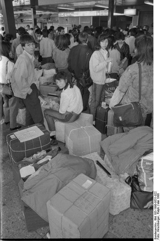 Foto: Vietnamesische Gastarbeiter aus Cottbus verlassen mit Chartermaschinen vom Flugplatz Schönefeld aus die DDR. Fotograf: ADN/Ralph Hirschberger, Berlin, 31. Mai 1990. Quelle: [https://commons.wikimedia.org/wiki/File:Bundesarchiv_Bild_183-1990-0531-022,_Berlin,_vietnamesische_Gastarbeiter.jpg Bundesarchiv Bild 183-1990-0531-022 / Wikimedia Commons], Lizenz: [https://creativecommons.org/licenses/by-sa/3.0/deed.de CC BY-SA 3.0] <br />Das Ende der DDR stellte auch das Bleiberecht der Migrantinnen in Frage. Es gab den Staat nicht mehr, für den sie eine begrenzte Aufenthaltserlaubnis hatten. Die rassistische Gewalt nahm massiv zu. Als besonderer Anreiz zur Ausreise wurde allen sog. Vertragsarbeitern, die das Land verließen, 3000 D-Mark Entschädigung angeboten. Die Betriebe organisierten den Rückflug. <br />Vgl. zu den Migrantinnen, die als „Vertragsarbeiter“, als Studierende oder politische Emigranten in die DDR kamen, die Webdokumentation „[https://bruderland.de/ Eigensinn im Bruderland]“ [18.10.2022] von Isabel Enzenbach, Mai-Phuong Kollath und Julia Oelkers.