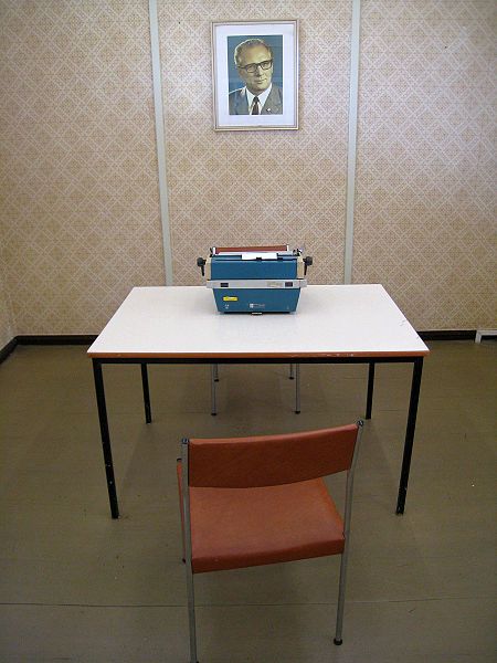 Ehemaliges Verhörzimmer an der DDR-Grenzübergangsstelle Marienborn, heute Teil der Ausstellung der Gedenkstätte Deutsche Teilung Marienborn. Fotograf:in: ChrisO, 4. September 2009, Quelle: [https://commons.wikimedia.org/wiki/File:Marienborn_interview_room.jpg Wikimedia Commons], Lizenz [https://creativecommons.org/licenses/by-sa/3.0/deed.en CC-BY-SA 3.0]